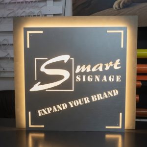 Custom laser-cut steel illuminated light box sign for Smart Signage by Smart Digital Media Paarl. Backlit LED signage with modern design and clean cut-out lettering reading "Smart Signage - Expand Your Brand", proudly manufactured in-house.
